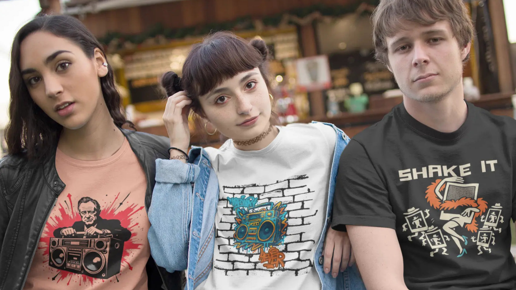 Three friends hanging out together outside while wearing graphic tees. 